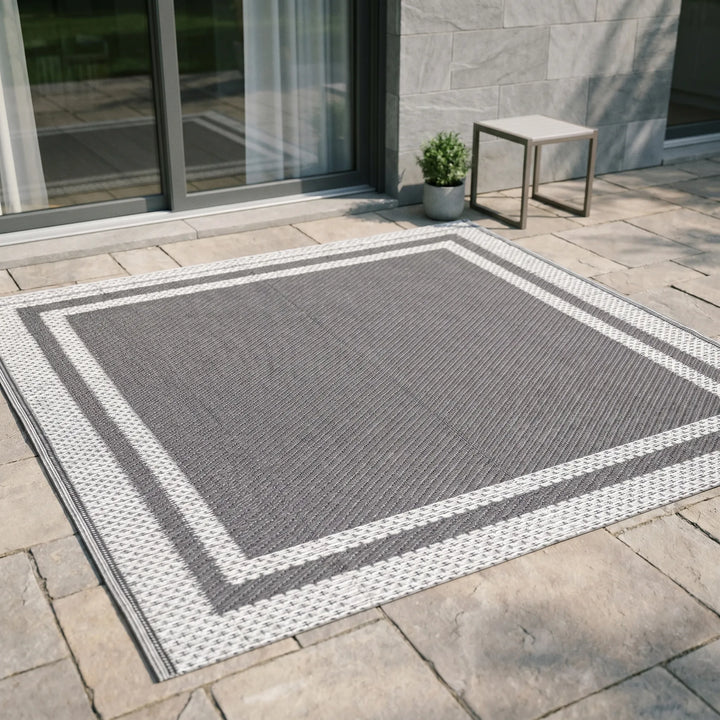 Rectangular modern outdoor area mat in grey white. Reversible geometric design, perfect deck & patio decor. Portable & easy clean.