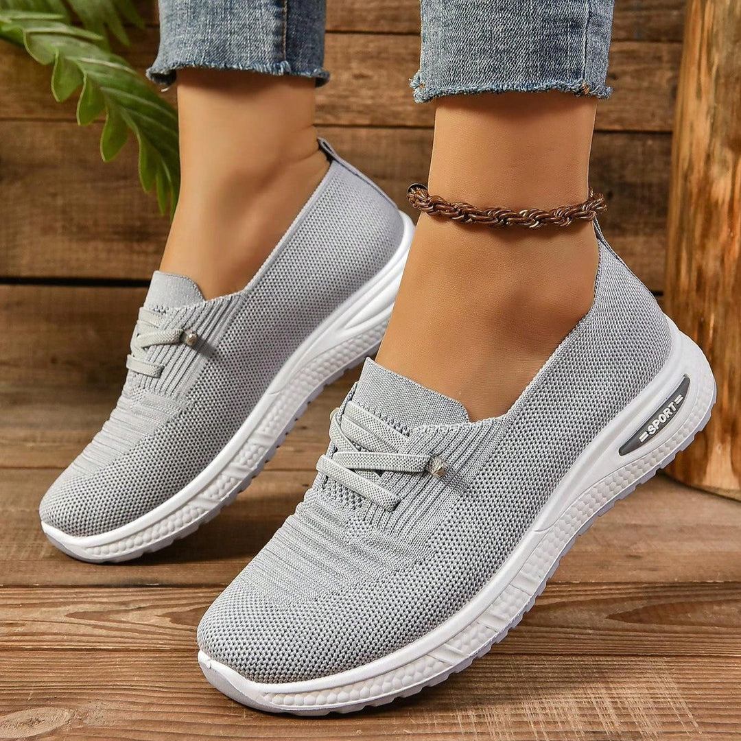 Athletic gray women's footwear with cushioned sole & strong arch support for active wear.