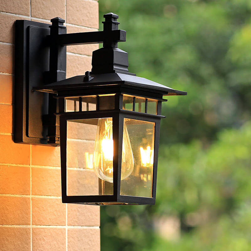 Close-up of modern rustic outdoor wall lantern, black aluminum. Waterproof exterior light enhances patio & garden decor.