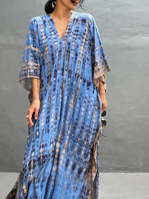 Full view: Stylish woman in vibrant tie-dye kaftan maxi dress, perfect for elegant beachwear.