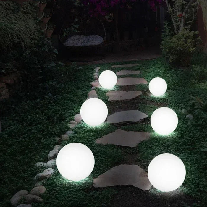 A child interacting with a GlowSphere rechargeable LED garden lamp.