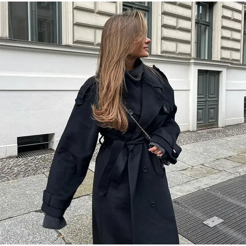 Fashionable woman wearing a classic double-breasted black trench coat. Elegant long outerwear for stylish seasonal looks.
