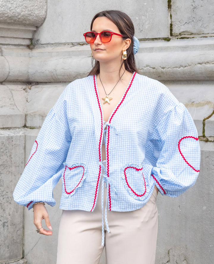 Model wearing a versatile women's tie-front blouse with ruffle and puff long sleeves, perfect for day to night.