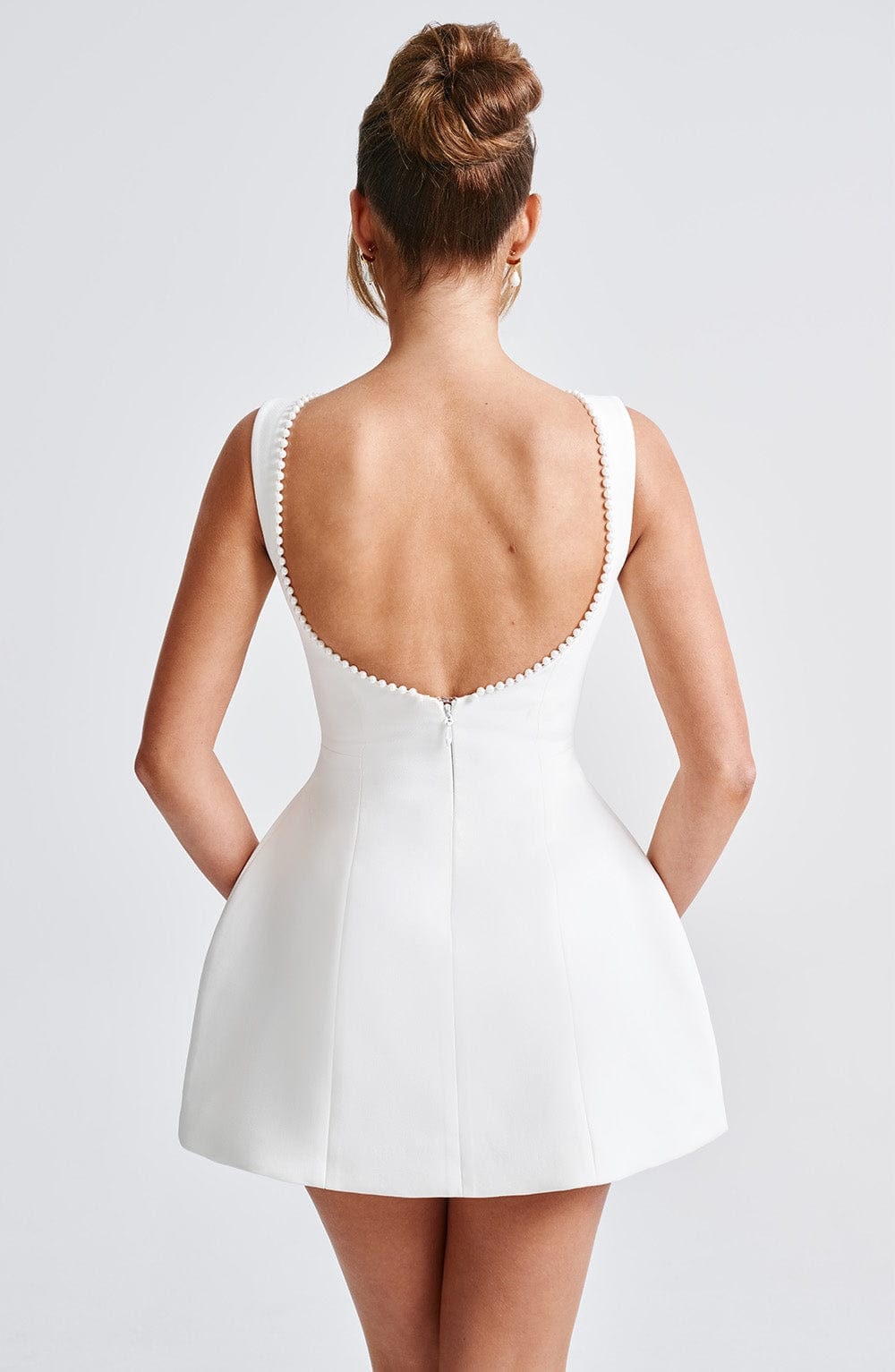 Sleeveless women's boat neck mini dress, featuring a sophisticated back bow, great for wedding guests.