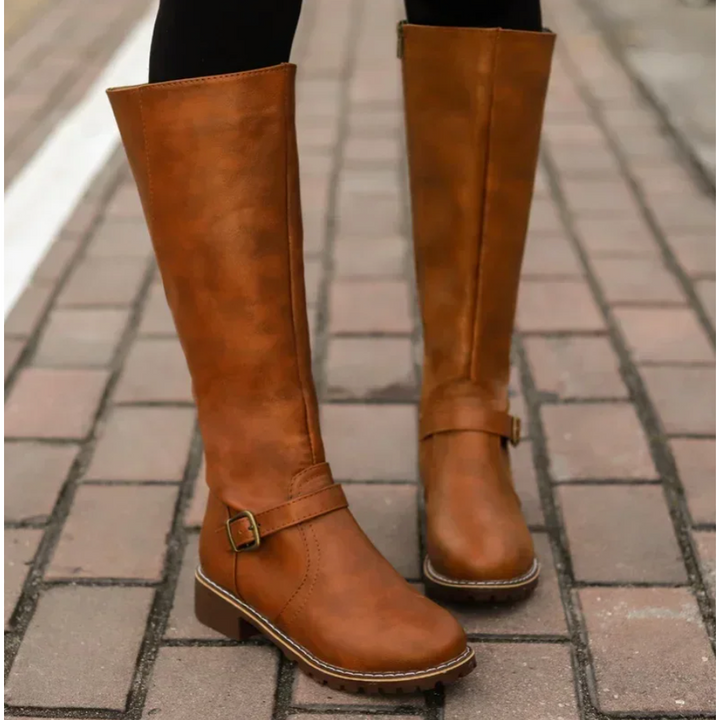 Women's riding-style knee-high boots in black with a chic buckle, functional zipper, and resilient lug sole.